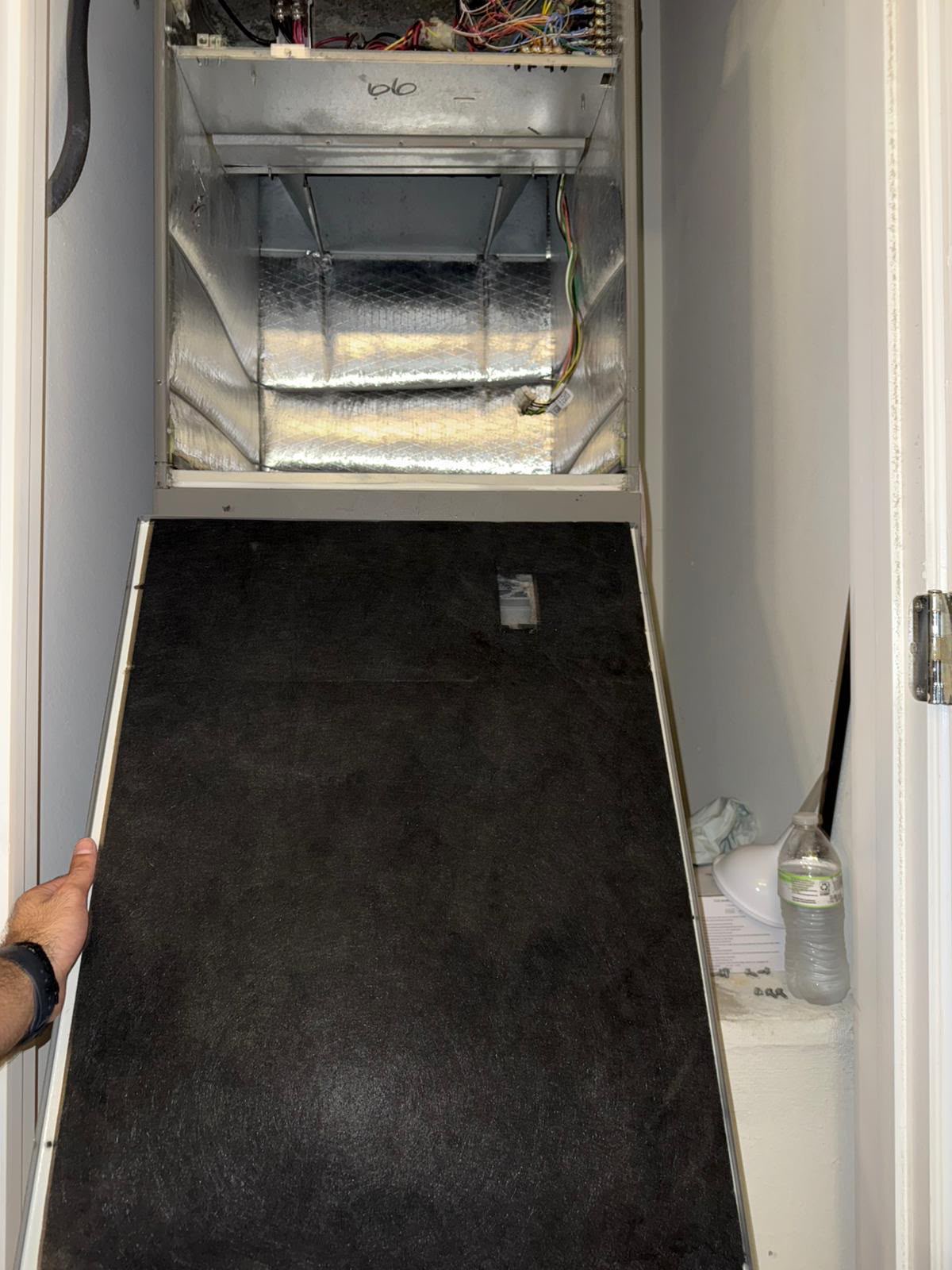 Technician holding a clean air filter in front of an A/C handler in Biscayne Park FL